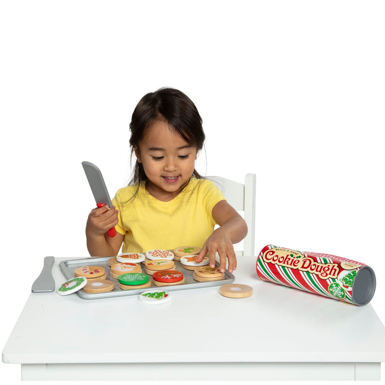 A child on white background with the Melissa & Doug Slice and Bake Wooden Christmas Cookie Play Food Set