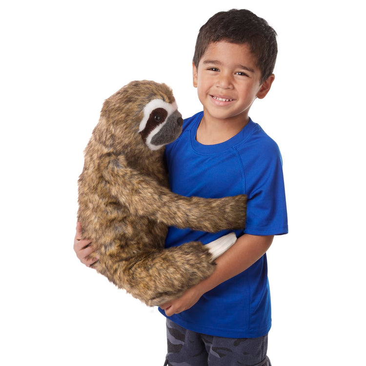 A child on white background with the Melissa & Doug Lifelike Plush Sloth Stuffed Animal (12W x 14.5H x 9D in)