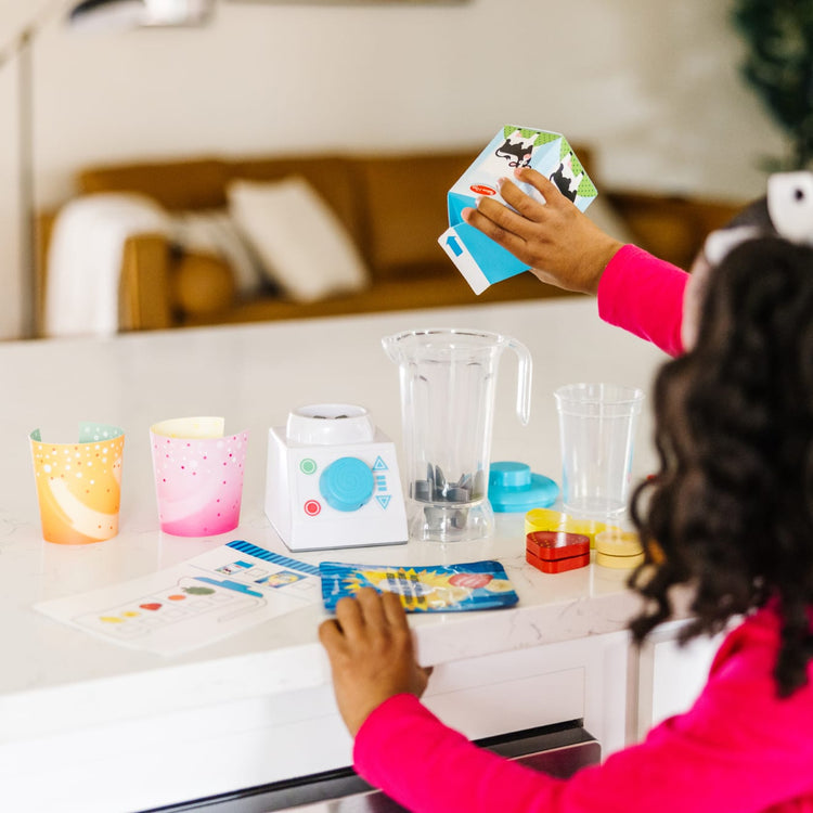 A kid playing with the Melissa & Doug Smoothie Maker Blender Set with Play Food (222 Pcs)