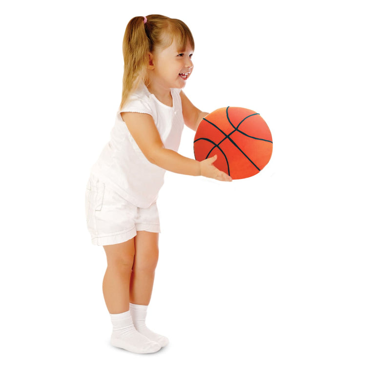 A child on white background with the Melissa & Doug Sports Throw Pillows With Mesh Storage Bag - Plush Basketball, Baseball, Soccer Ball, and Football