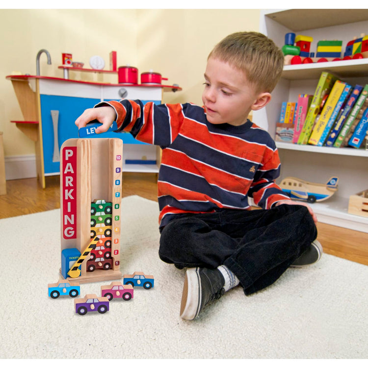 A kid playing with the Melissa & Doug Stack & Count Wooden Parking Garage With 10 Cars