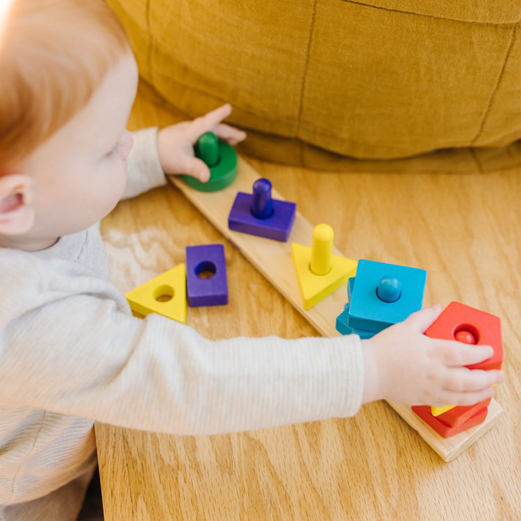 A kid playing with the Melissa & Doug Stack and Sort Board - Wooden Educational Toy With 15 Solid Wood Pieces