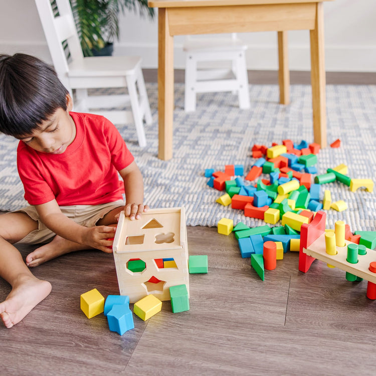 A kid playing with the Melissa & Doug Stack, Sort & Pound Wooden Toy Collection (Building Blocks, Shape Sorter, Pounding Bench)