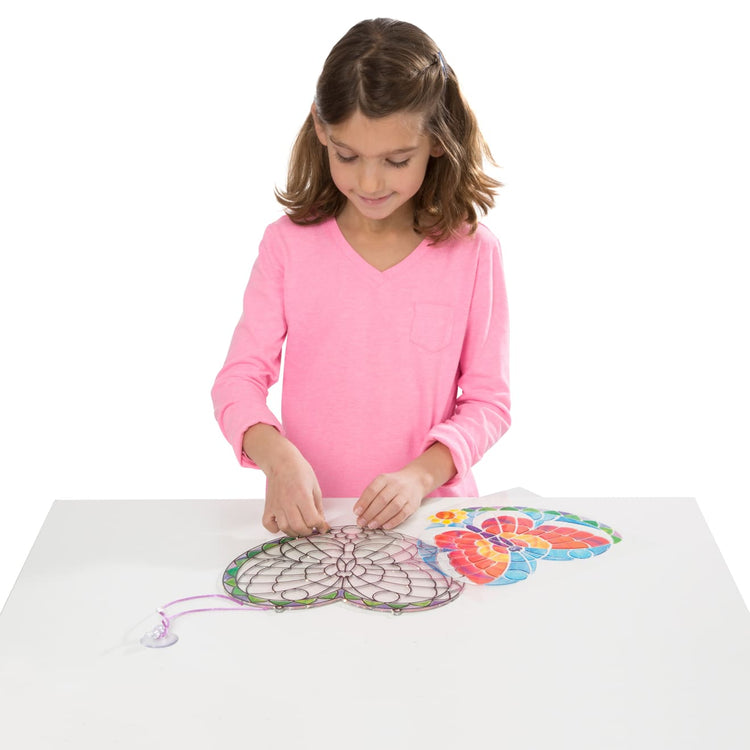A child on white background with the Melissa & Doug Stained Glass Made Easy Activity Kit: Butterfly - 140+ Stickers