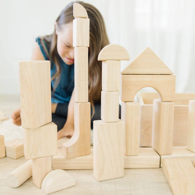 A kid playing with the Melissa & Doug Standard Unit Solid-Wood Building Blocks With Wooden Storage Tray (60 pcs)