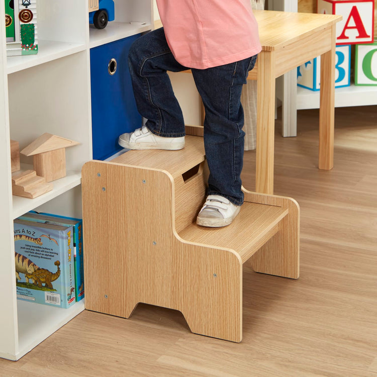 A kid playing with the Melissa & Doug Kids Wooden Step Stool - Light Natural Finish