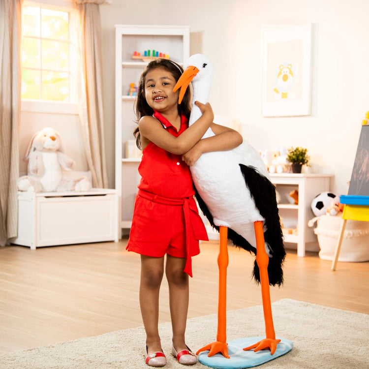A kid playing with the Melissa & Doug Lifelike Plush Stork Giant Standing Stuffed Animal (3+ Feet Tall)