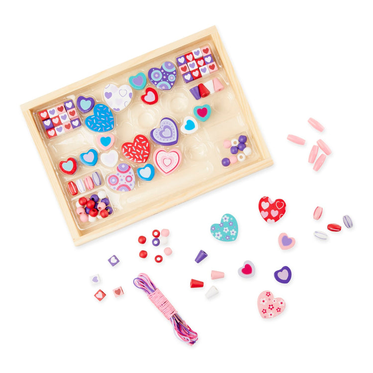 The loose pieces of the Melissa & Doug Created by Me! Heart Beads Wooden Bead Kit, 120+ Beads and 5 Cords for Jewelry-Making
