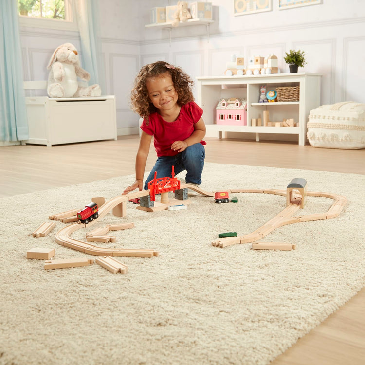 A kid playing with the Melissa & Doug Swivel Bridge Wooden Train Set (47 pcs)