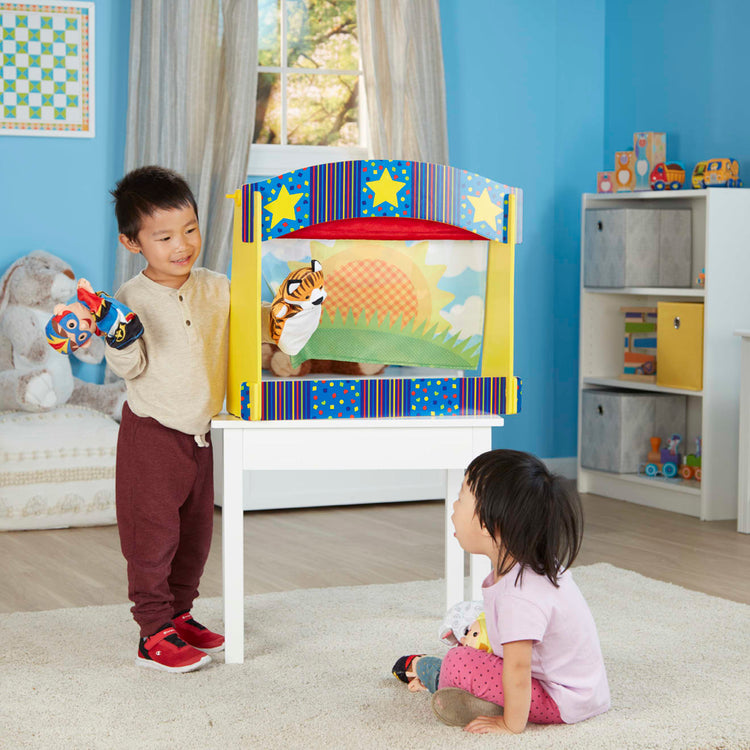 A kid playing with the Melissa & Doug Tabletop Puppet Theater - Sturdy Wooden Construction