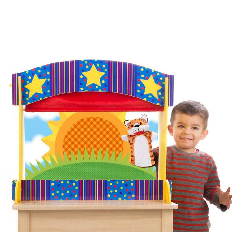 A child on white background with the Melissa & Doug Tabletop Puppet Theater - Sturdy Wooden Construction