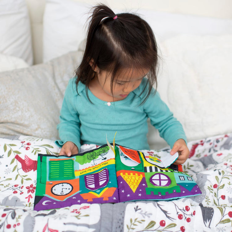 A kid playing with the Melissa & Doug Soft Activity Baby Book - The Wonderful World of Peekaboo!