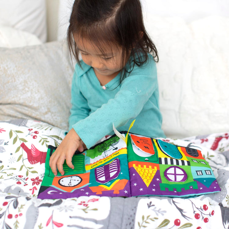 A kid playing with the Melissa & Doug Soft Activity Baby Book - The Wonderful World of Peekaboo!
