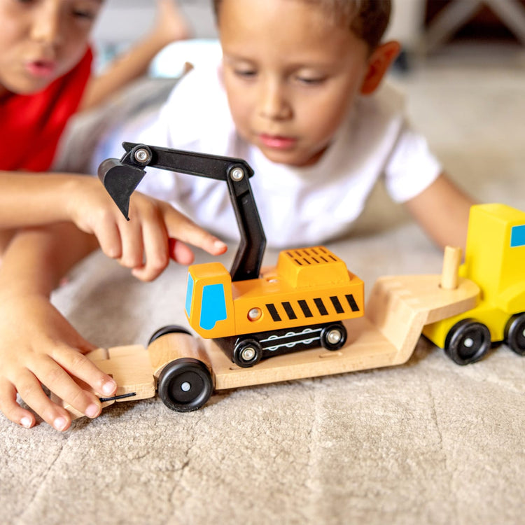 A kid playing with the Melissa & Doug Trailer and Excavator Wooden Vehicle Set (3 pcs)