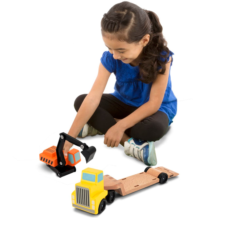 A child on white background with the Melissa & Doug Trailer and Excavator Wooden Vehicle Set (3 pcs)