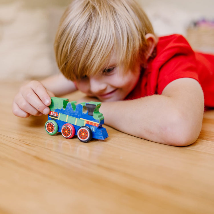 A kid playing with the Melissa & Doug Train Wooden Craft Kit
