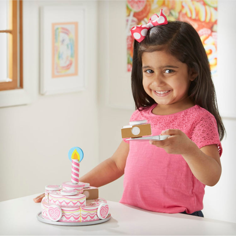 A kid playing with the Melissa & Doug Triple-Layer Party Cake Wooden Play Food Set