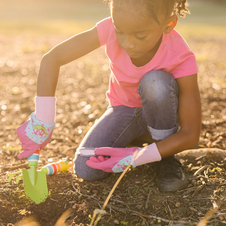 A kid playing with the Melissa & Doug Dixie and Trixie Ladybug Good Gripping Gardening Gloves