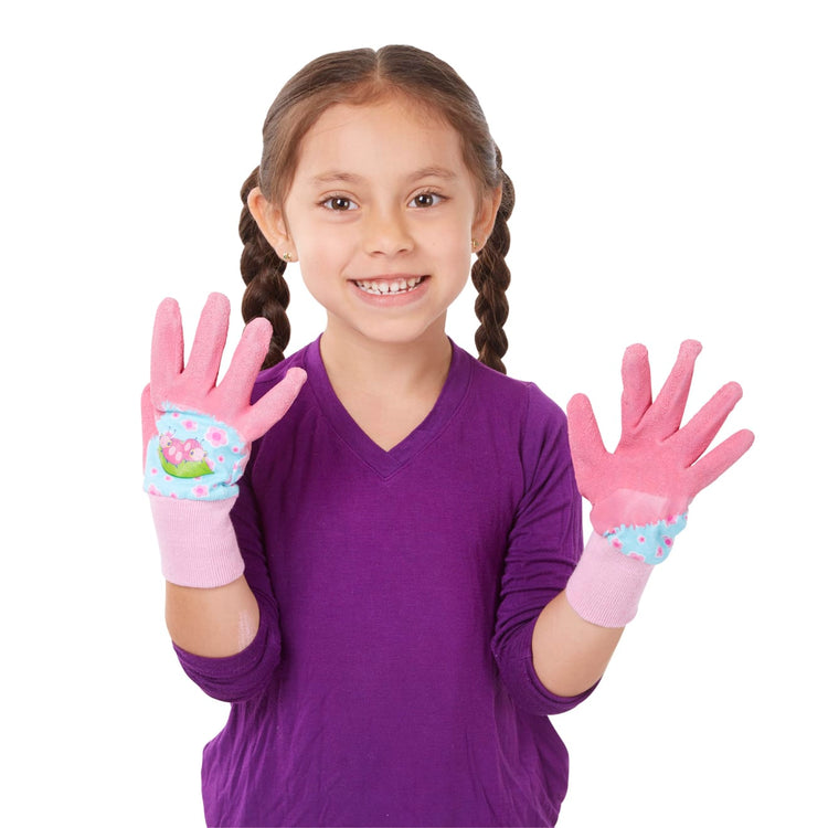 A child on white background with the Melissa & Doug Dixie and Trixie Ladybug Good Gripping Gardening Gloves