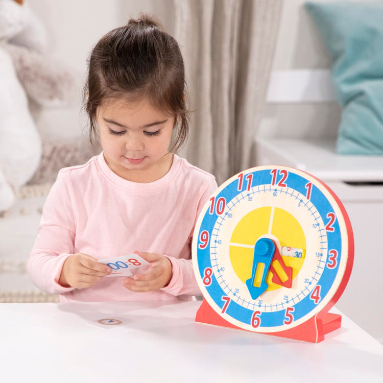 A kid playing with the Melissa & Doug Turn & Tell Wooden Clock - Educational Toy With 12+ Reversible Time Cards