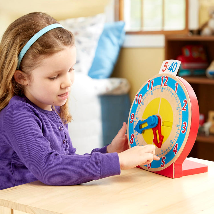 A kid playing with the Melissa & Doug Turn & Tell Wooden Clock - Educational Toy With 12+ Reversible Time Cards