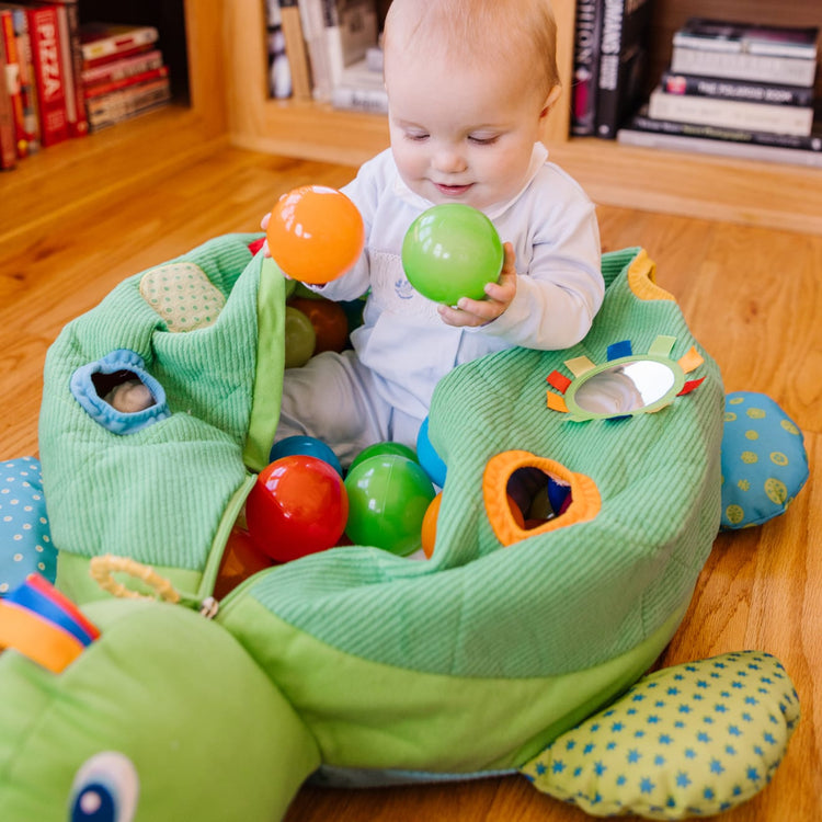 A kid playing with the Melissa & Doug K's Kids Turtle Ball Pit With 60 Balls