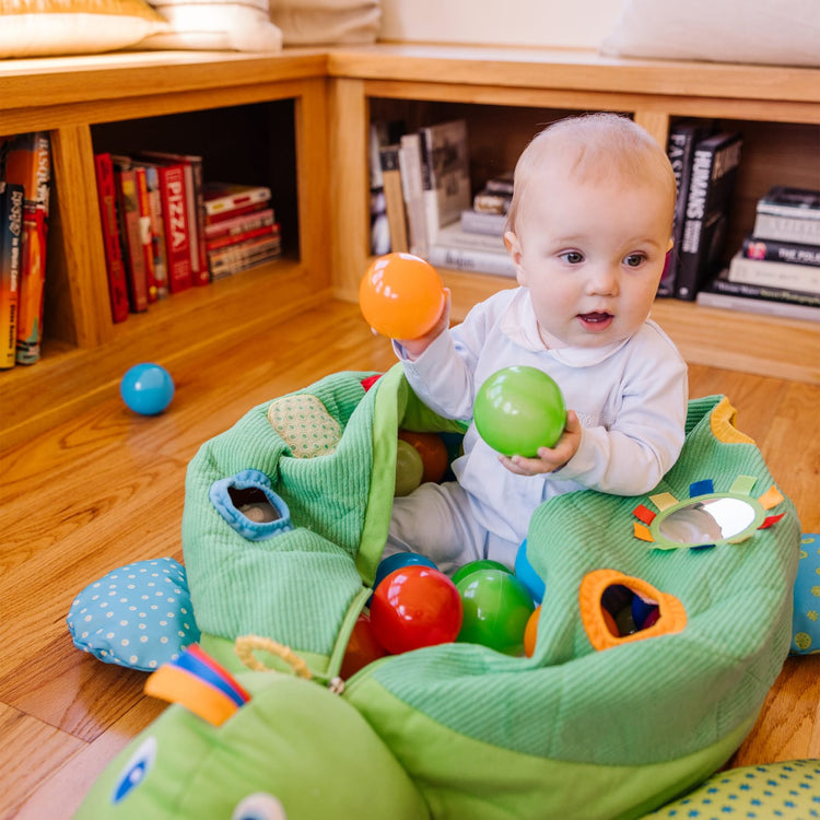 A kid playing with the Melissa & Doug K's Kids Turtle Ball Pit With 60 Balls