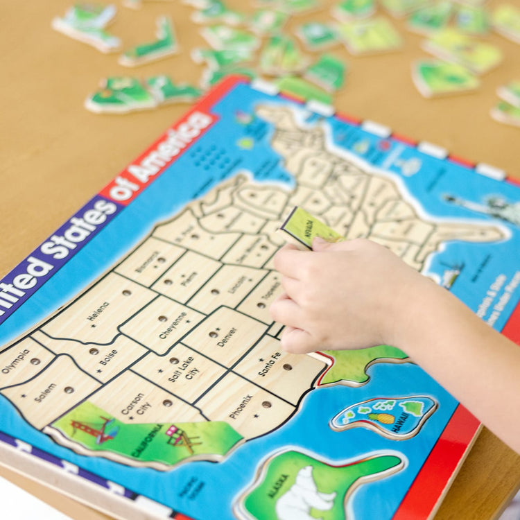 A kid playing with the Melissa & Doug USA Map Sound Puzzle - Wooden Puzzle With Sound Effects (40 pcs)