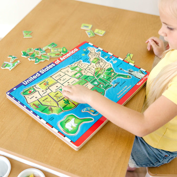 A kid playing with the Melissa & Doug USA Map Sound Puzzle - Wooden Puzzle With Sound Effects (40 pcs)