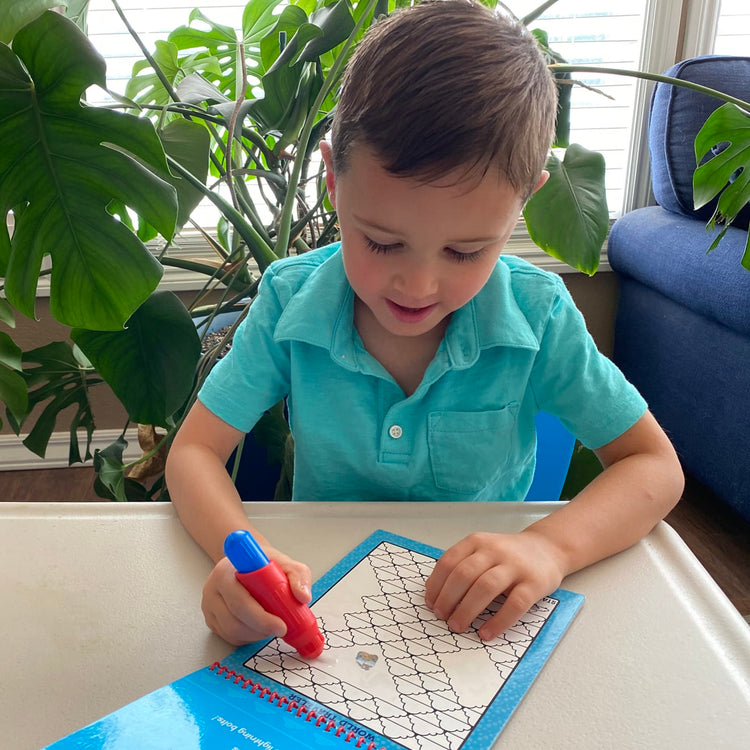 A kid playing with the Melissa & Doug On the Go Water Wow! Reusable Water-Reveal Activity Pad – Vehicle Pathways