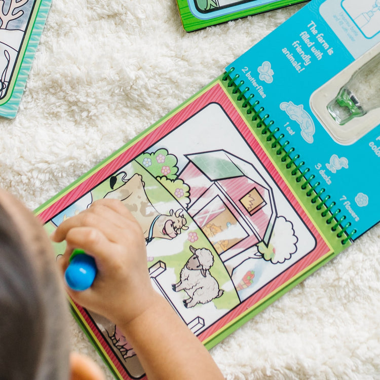 A kid playing with the Melissa & Doug On the Go Water Wow! Reusable Water-Reveal Activity Pads, 3-pk, Vehicles, Animals, Safari