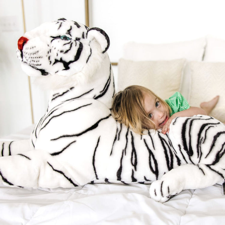 A kid playing with the Melissa & Doug Giant Siberian White Tiger - Lifelike Stuffed Animal (over 5 feet long)