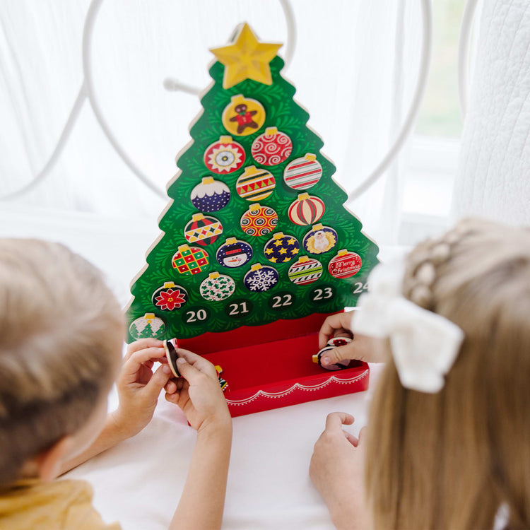 A kid playing with the Melissa & Doug Wooden Religious Advent Calendar - Magnetic Christmas Tree, 25 Magnets