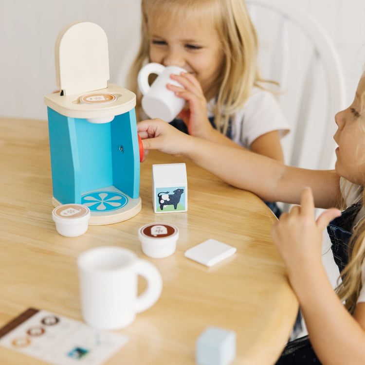 A kid playing with the Melissa & Doug 11-Piece Brew and Serve Wooden Coffee Maker Set - Play Kitchen Accessories