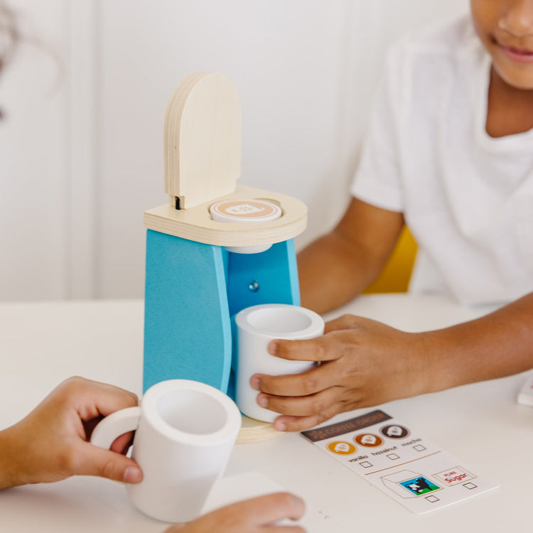 A kid playing with the Melissa & Doug 11-Piece Brew and Serve Wooden Coffee Maker Set - Play Kitchen Accessories