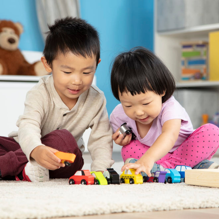A kid playing with the Melissa & Doug Wooden Cars Vehicle Set in Wooden Tray