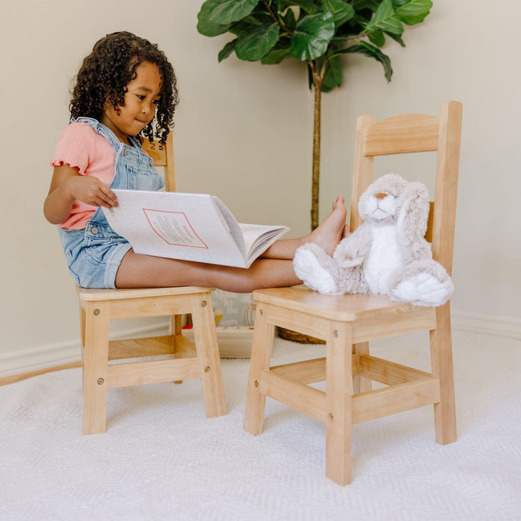 A kid playing with the Melissa & Doug Solid Wood Chairs, Set of 2 - Light Finish Furniture for Playroom