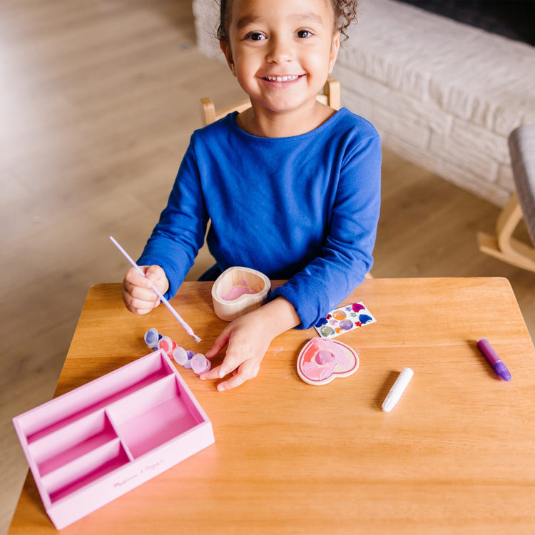 A kid playing with the Melissa & Doug Decorate-Your-Own Wooden Heart Box Craft Kit