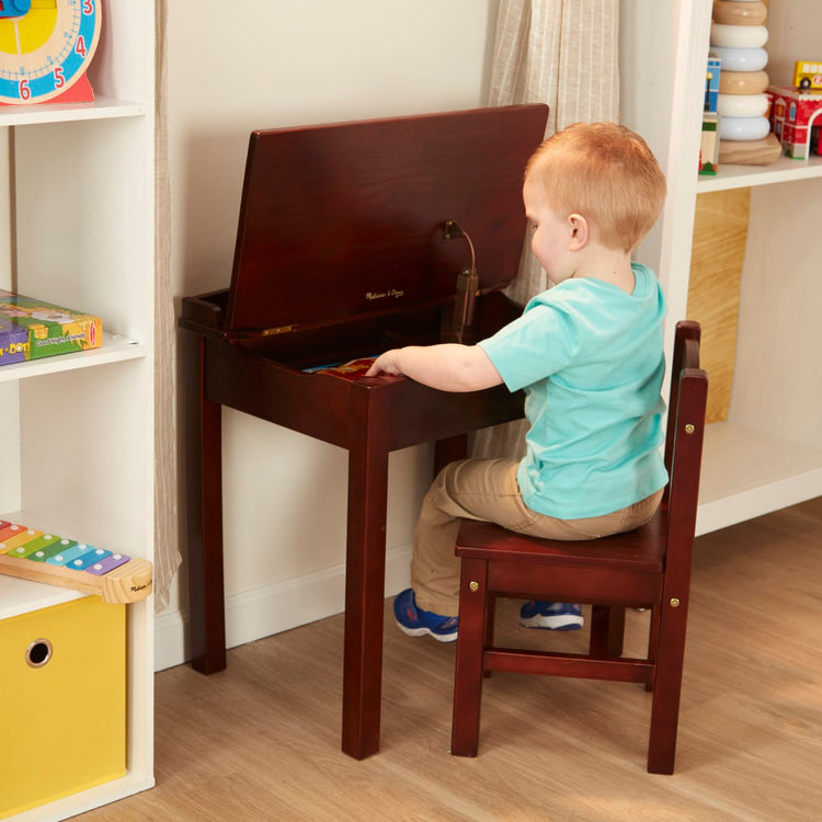 A kid playing with the Melissa & Doug Wooden Child's Lift-Top Desk & Chair - Espresso