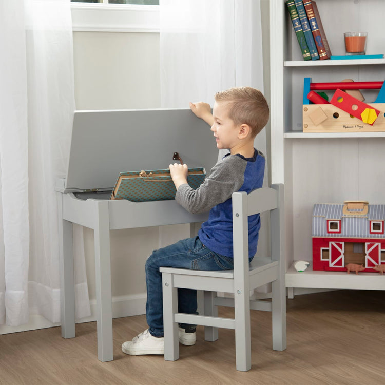 A kid playing with the Wooden Lift-Top Desk & Chair - Gray