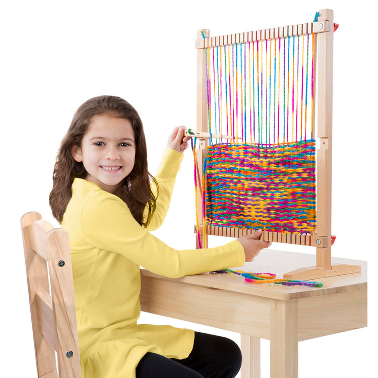 A child on white background with the Melissa & Doug Wooden Multi-Craft Weaving Loom: Extra-Large Frame (22.75 x 16.5 inches)