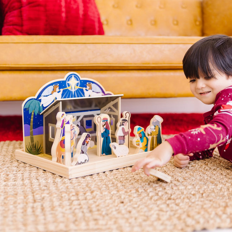 A kid playing with the Melissa & Doug Classic Wooden Christmas Nativity Set With 4-Piece Stable and 11 Wooden Figures