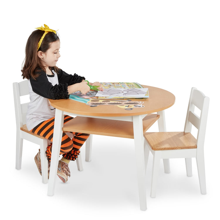 A child on white background with the Melissa & Doug Wooden Round Table and 2 Chairs Set – Kids Furniture for Playroom, Light Woodgrain and White 2-Tone Finish