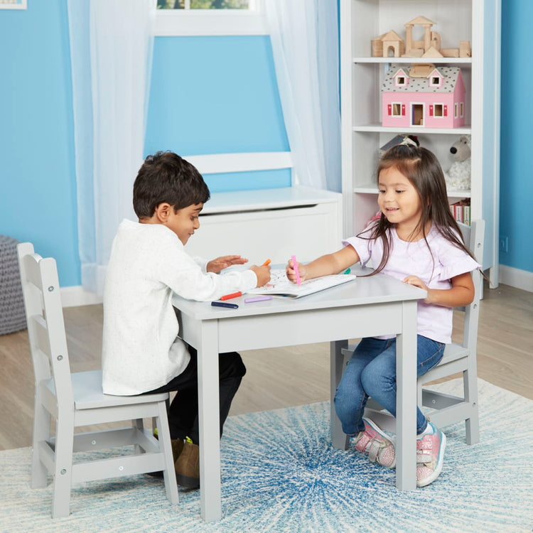 A kid playing with the Melissa & Doug Kids Furniture Wooden Table and 2 Chairs - Gray