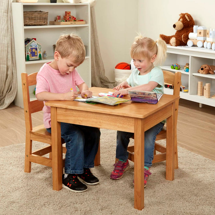 A kid playing with the Melissa & Doug Solid Wood Table and 2 Chairs Set - Light Finish Furniture for Playroom