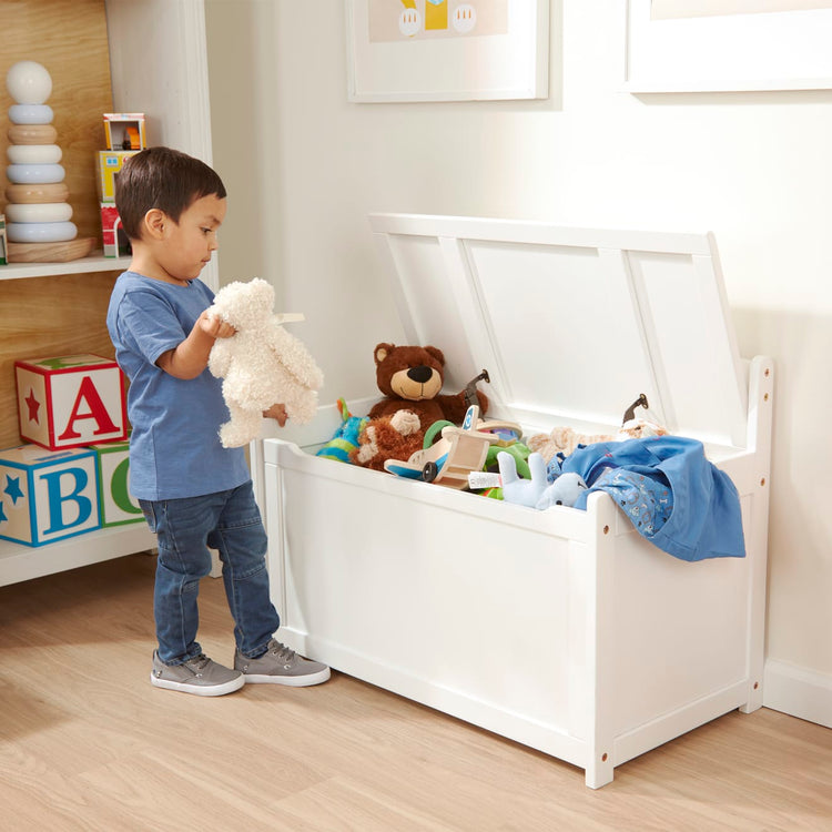 A kid playing with the Melissa & Doug Wooden Toy Chest (White)
