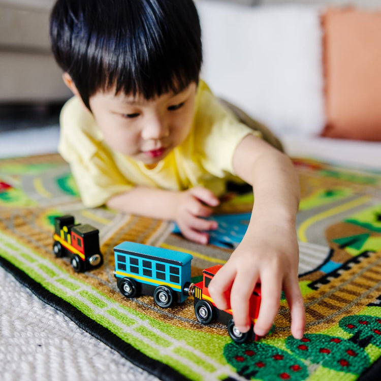 A kid playing with the Melissa & Doug Wooden Train Cars - 8 3-Inch Wheeled Trains in Crate