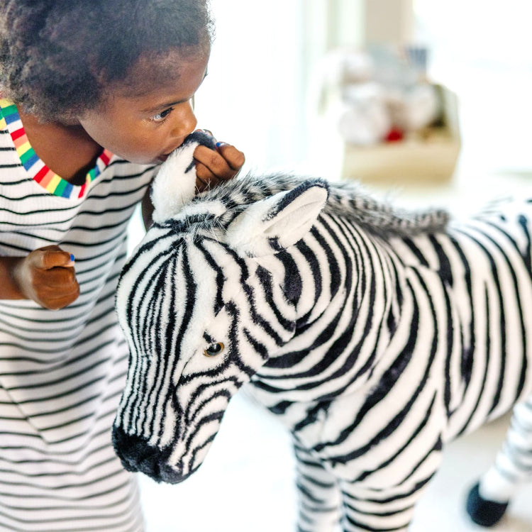 A kid playing with the Melissa & Doug Giant Striped Zebra - Lifelike Stuffed Animal (nearly 3 feet tall)